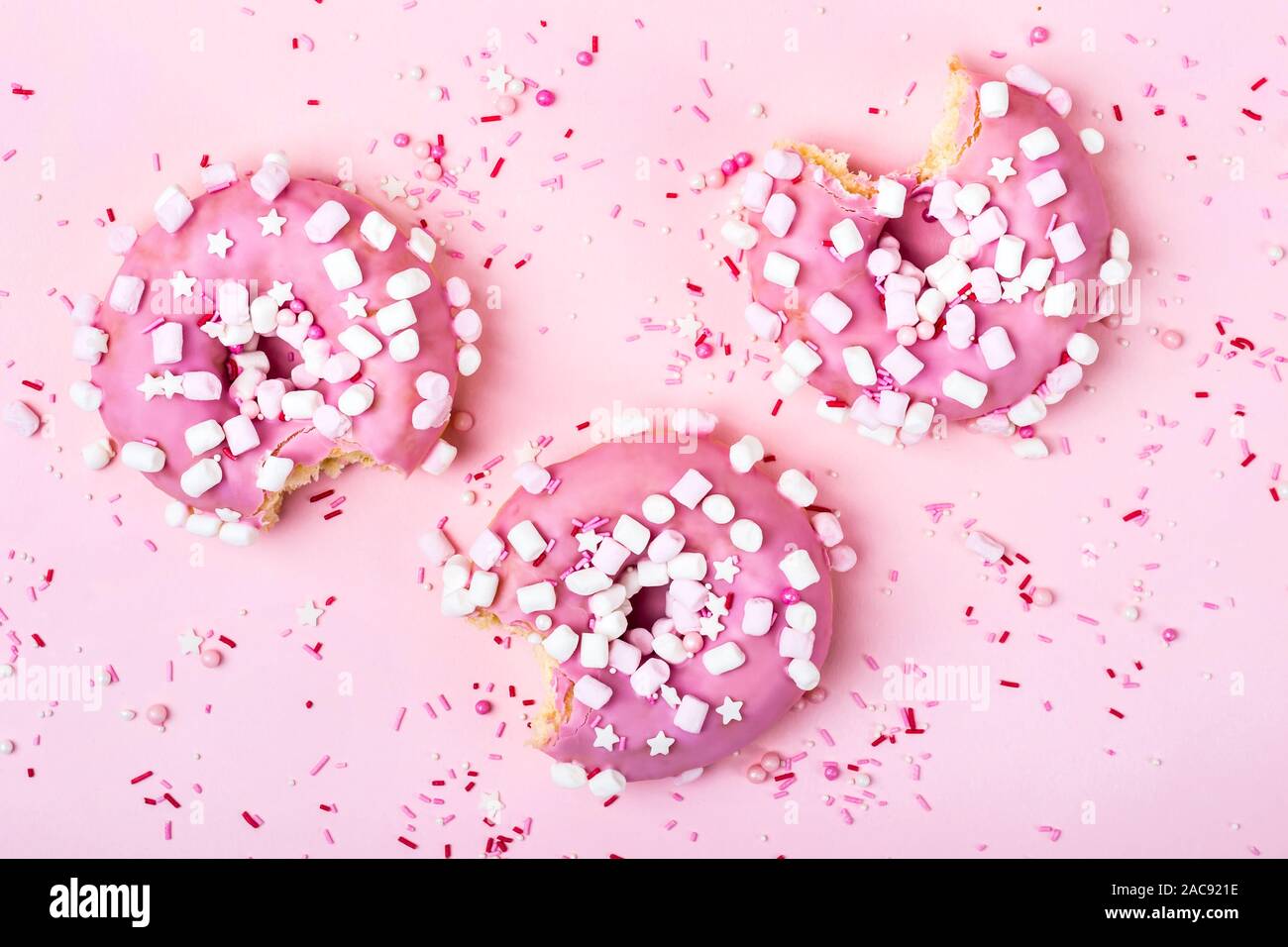 Layout creativo fatto di rosa morso ciambelle con marshmallows. Concetto di cibo. Foto Stock