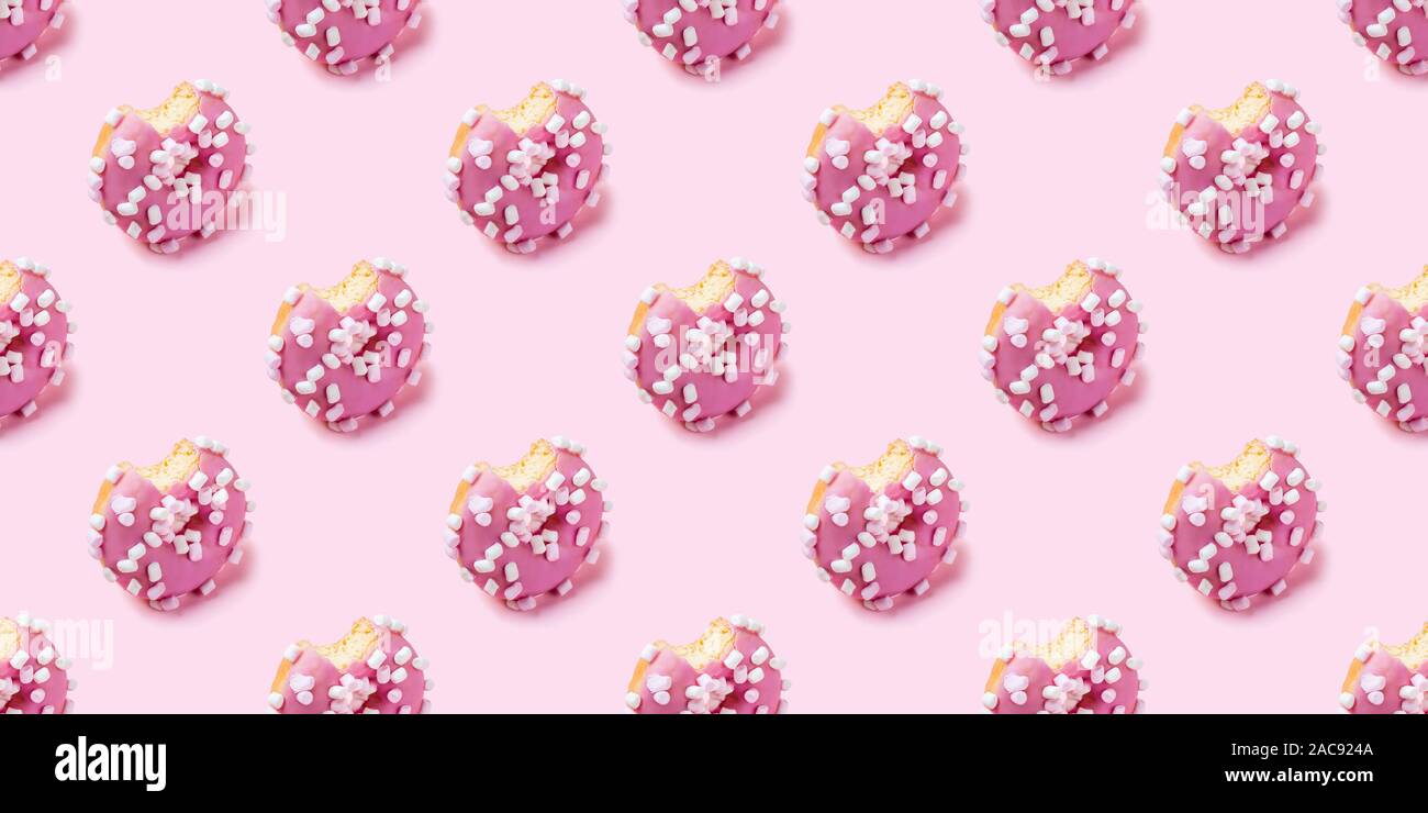 Seamless texture di morso glassa rosa ciambella con marshmallows su sfondo rosa, vista isometrica. Foto Stock