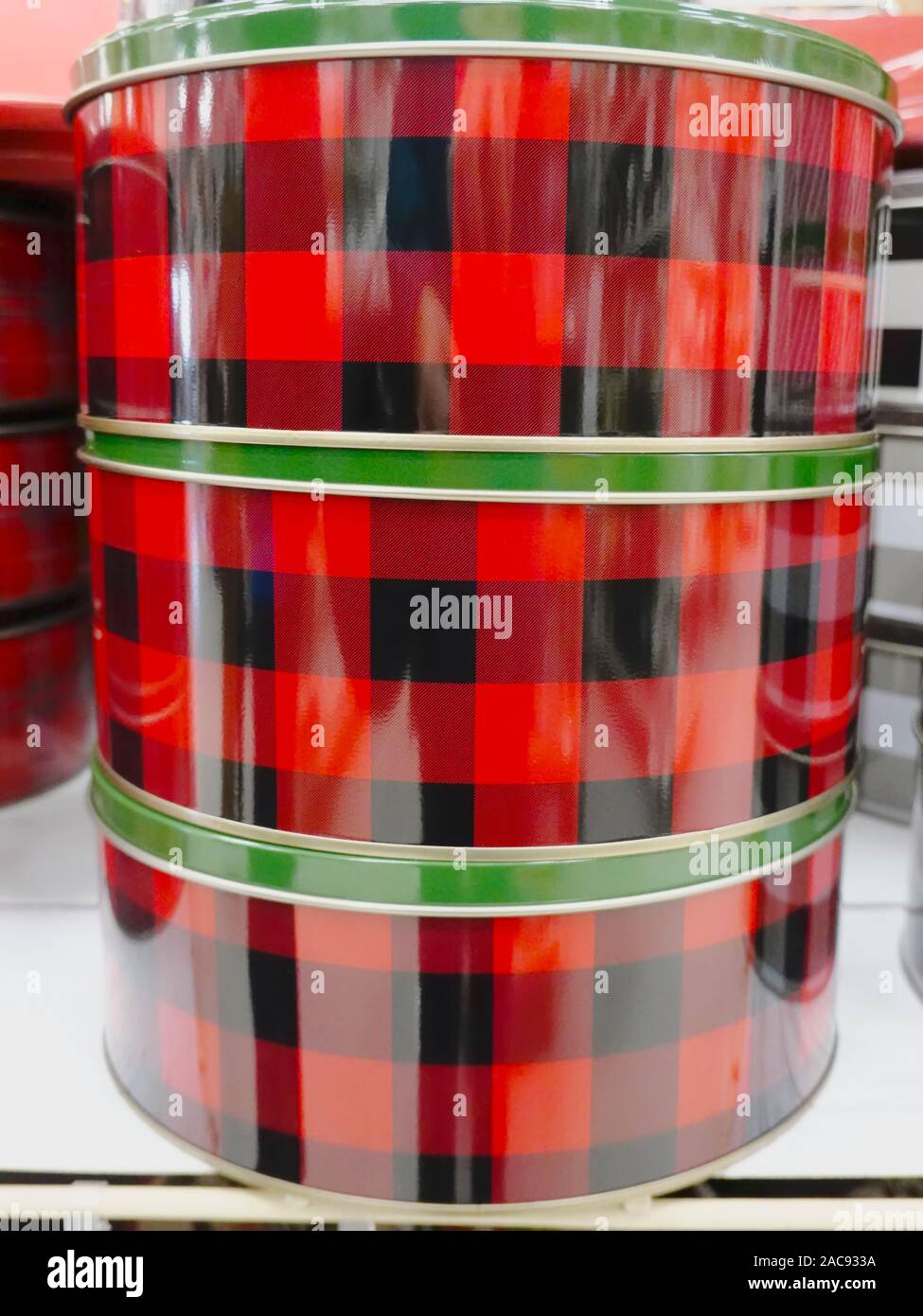 Tre tini regalo di Natale in plaid rosso e nero con coperchi verdi impilati su uno scaffale in un negozio di artigianato. Bassa terra, British Columbia, Canada Foto Stock