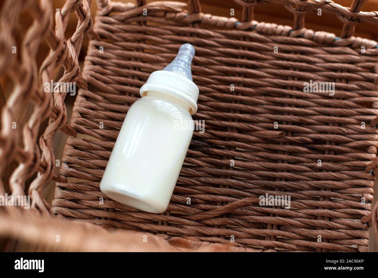 Bottiglia con latte materno per il bambino nel cesto di paglia. La maternità e la cura del bambino concetto. Vista superiore, copia gratuita dello spazio. Foto Stock