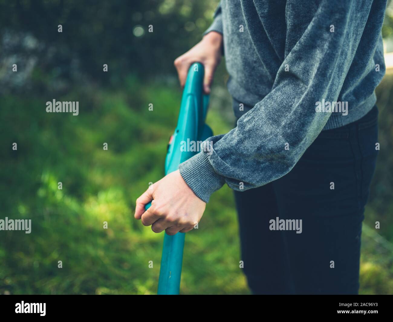 Una giovane donna è il taglio del prato utilizzando un decespugliatore di erba Foto Stock