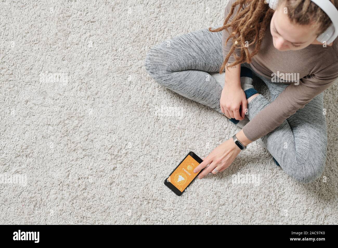 Attivo contemporanea ragazza seduta sul pavimento e andando a guardare video di yoga Foto Stock