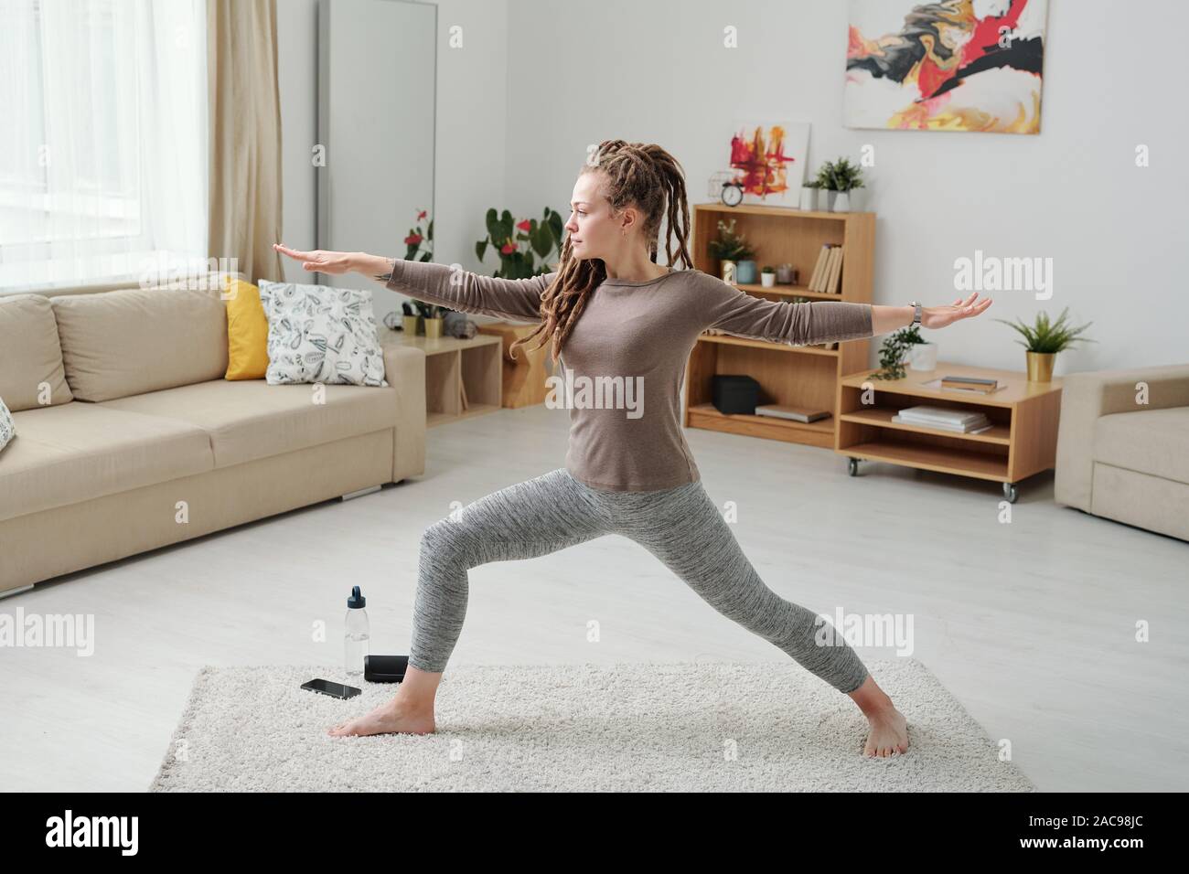 Montare la ragazza di leggins e pullover stretching gambe e braccia durante l'esercizio Foto Stock