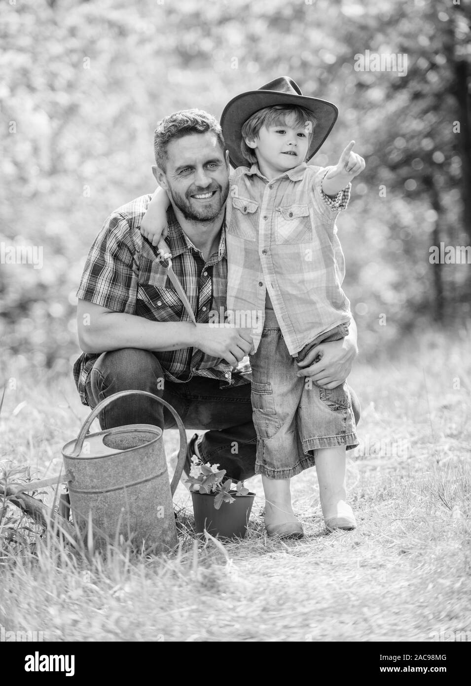Il pensiero di ecologia. Eco farm. felice giornata della terra. Albero genealogico nursering. annaffiatoio, pot e zappa. Attrezzature da giardino. piccolo bambino aiutare il padre nel lontano Foto Stock