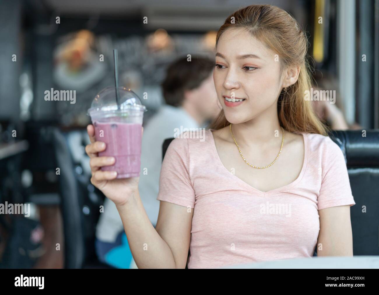 Donna che mantiene un bicchiere di mirtillo frullati in una caffetteria Foto Stock