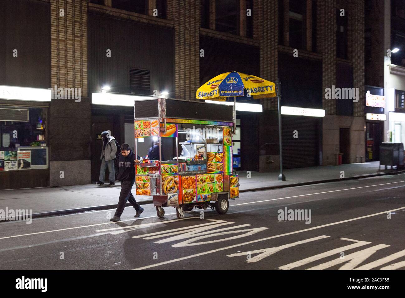 Hot Dog carrello e vendor spostando il suo carrello, Midtown, New York City, Stati Uniti d'America Foto Stock