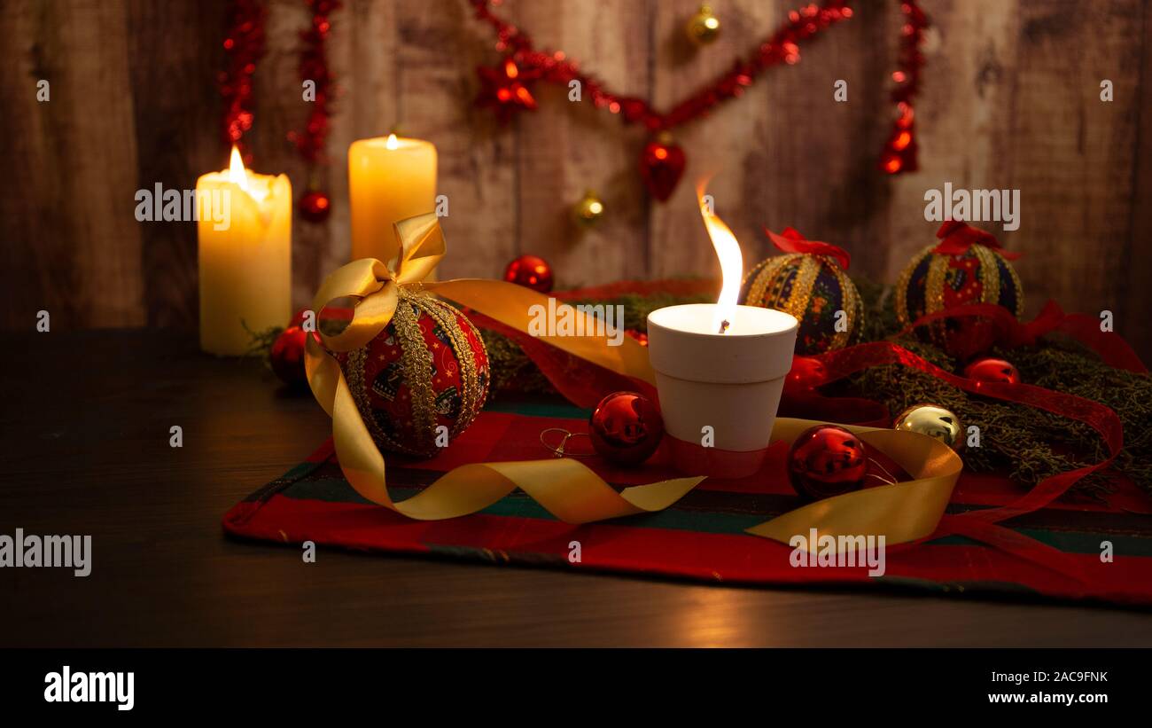Candela accesa con grande fiamma sulla tavola di Natale con panno attorno a  rami di pino, decoupage baubles, con candele accese e da appendere  decorazione di Natale su Foto stock - Alamy