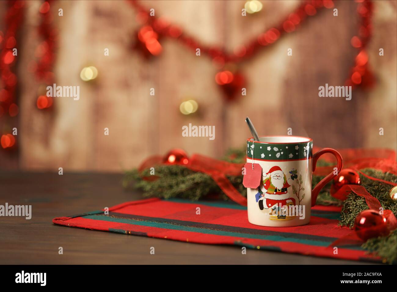 Natale la tazza con il pensile tè vuoto etichetta sulla tavola di Natale con panno attorno a rami di pino rosso e baubles appeso natale decorazione su legno Foto Stock