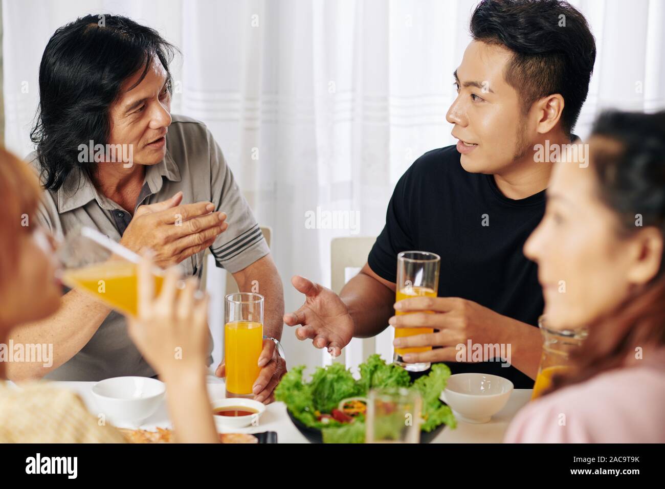 Vietnamita gravi padre e figlio adulto parlando a cena di famiglia a casa Foto Stock