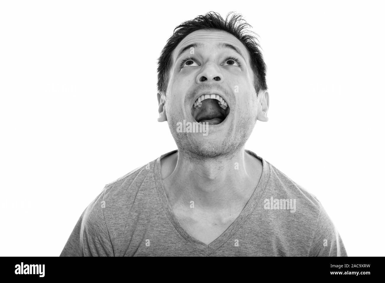 Studio shot di sorpresa felice giovane uomo sorridente e guardando verso l'alto mentre la bocca di apertura Foto Stock