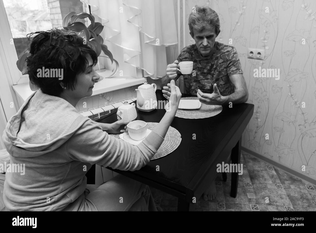 Bianco e nero foto concettuale di un adulto giovane marito e moglie durante la cena e guardando i telefoni ignorare e non comunicante con ciascuna Foto Stock