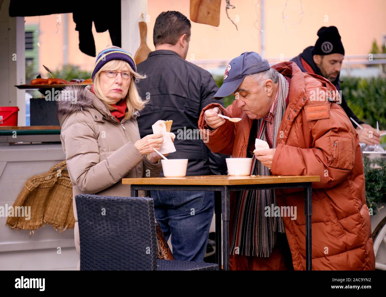 Paio mangiare fagioli stufati servite in tazze monouso a alimentare tabella di stallo durante il riposo. Mercatino di Natale a Zagabria, Croazia Foto Stock