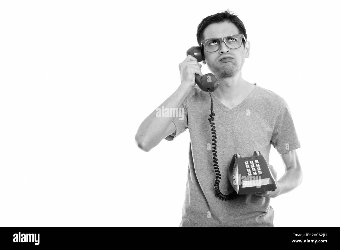 Studio shot di infastiditi giovane uomo parlando al telefono vecchio pensiero, mentre Foto Stock