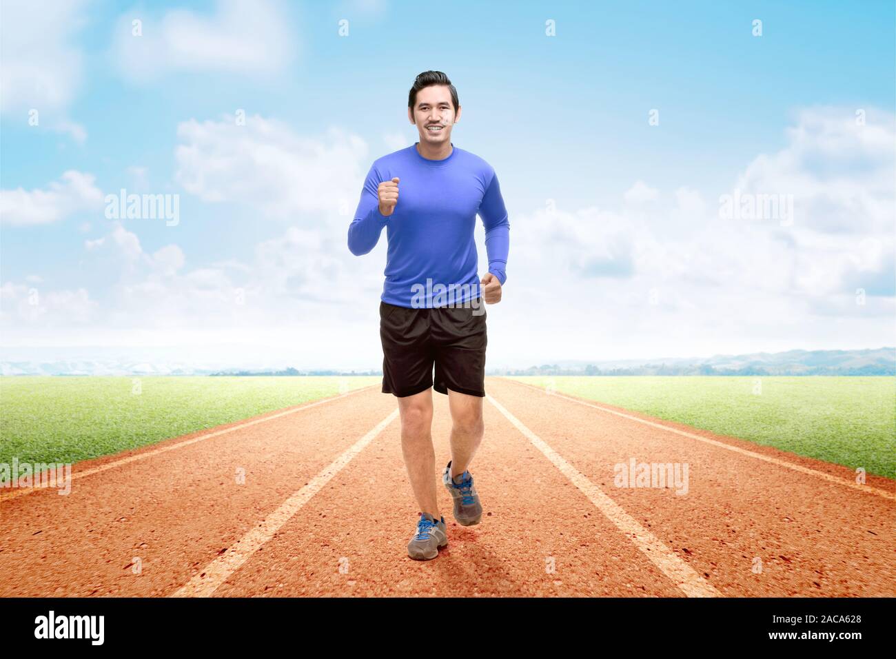 Asian runner uomo che corre sulla via di corsa con un cielo blu sullo sfondo Foto Stock