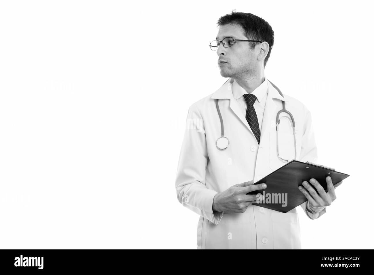 Vista di profilo del giovane medico tenendo clipboard mentre guarda lontano Foto Stock