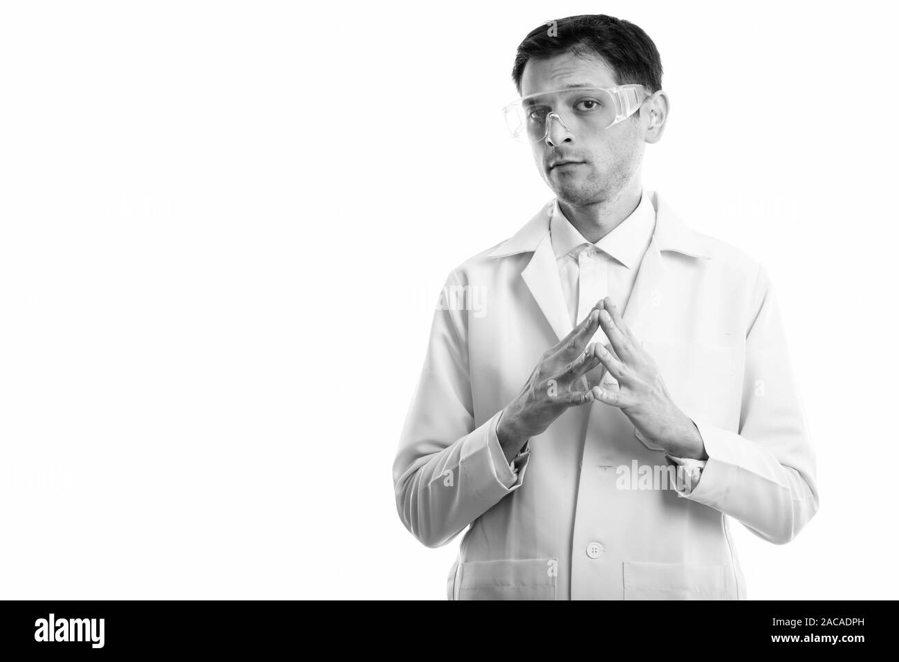 Studio shot del giovane medico che indossa gli occhiali di protezione con le dita insieme Foto Stock