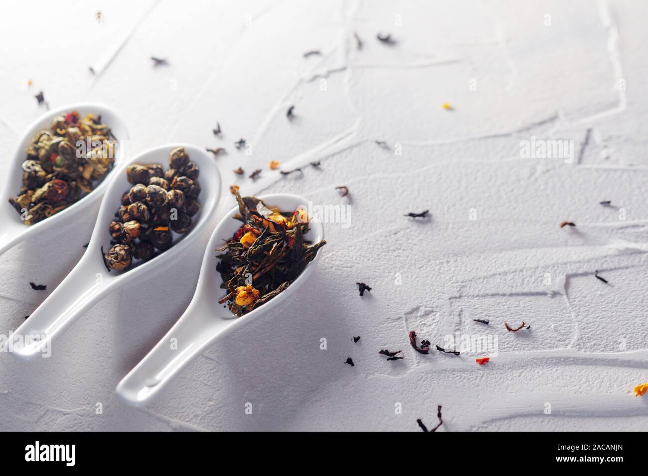 Diverse varietà di foglie di tè in bianco misurini su un bianco sullo sfondo a trama. Per preparare il tè, un delizioso e sano bevanda di tè cinese Foto Stock