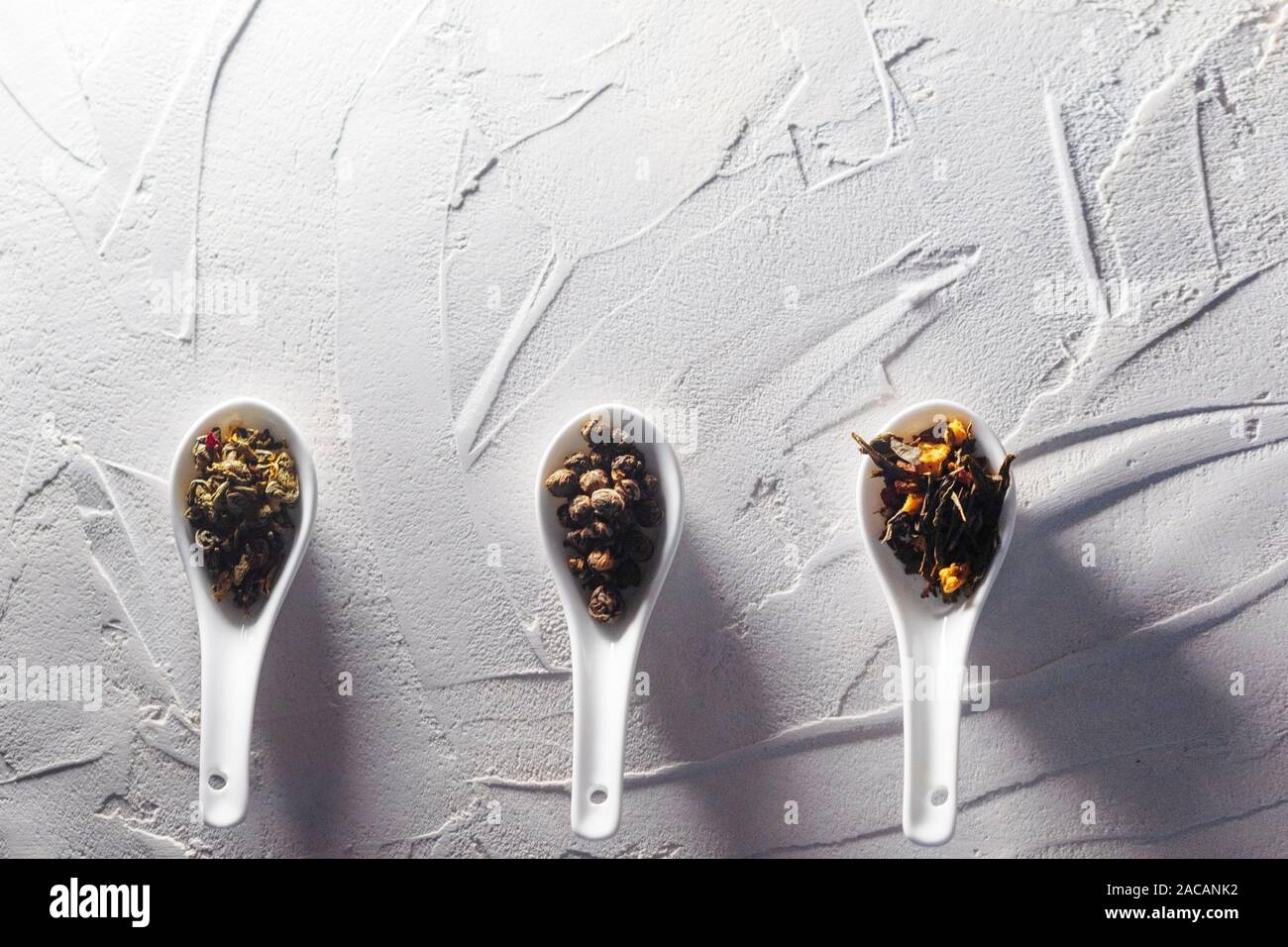 Diverse varietà di foglie di tè in bianco misurini su un bianco sullo sfondo a trama. Per preparare il tè, un delizioso e sano bevanda di tè cinese Foto Stock