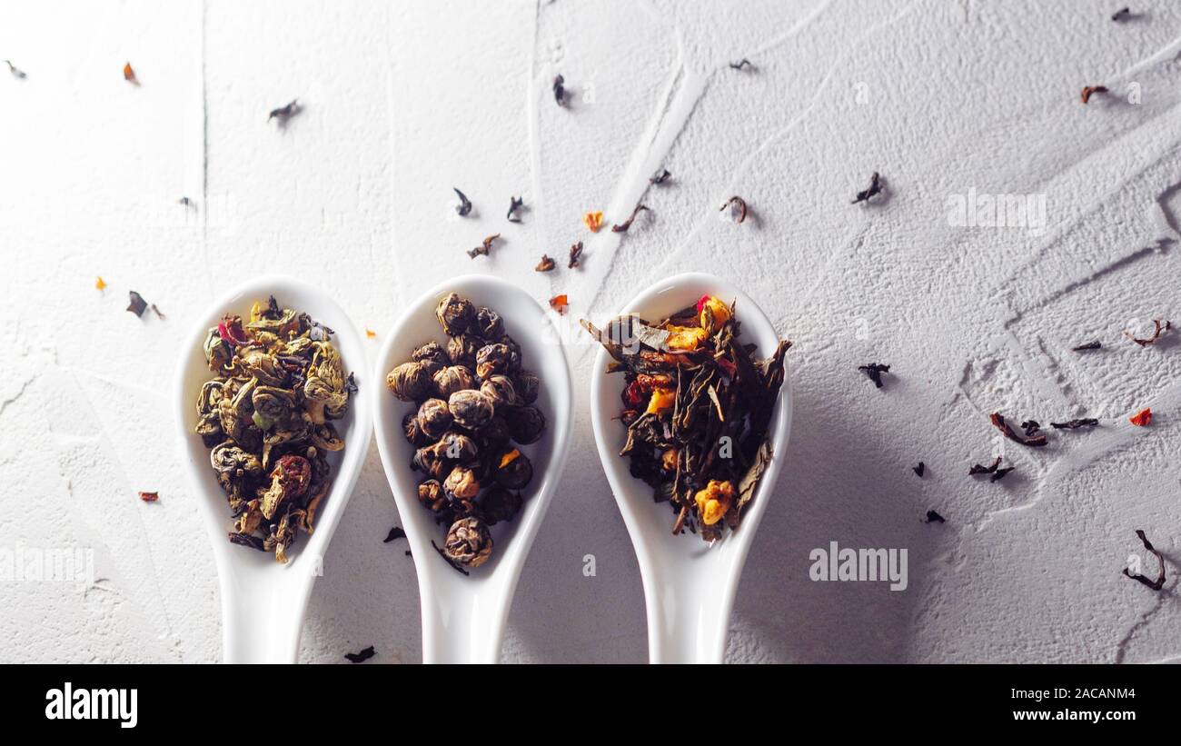 Diverse varietà di foglie di tè in bianco misurini su un bianco sullo sfondo a trama. Per preparare il tè, un delizioso e sano bevanda di tè cinese Foto Stock