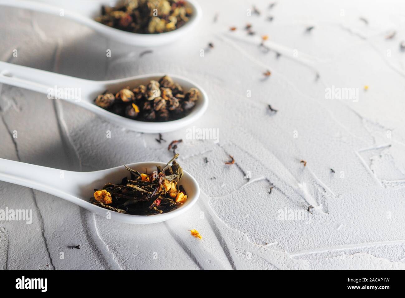 Diverse varietà di foglie di tè in bianco misurini su un bianco sullo sfondo a trama. Per preparare il tè, un delizioso e sano bevanda di tè cinese Foto Stock