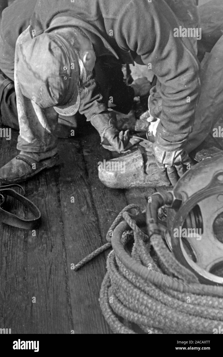 Schiffsarbeiter hilft Bojen Taucher in Taucheranzug, Emden, Niedersachsen, Deutschland, 1950. Nave lavoratore aiuta a boe subacquei nella muta, Emden, Bassa Sassonia, Germania, 1950s. Foto Stock