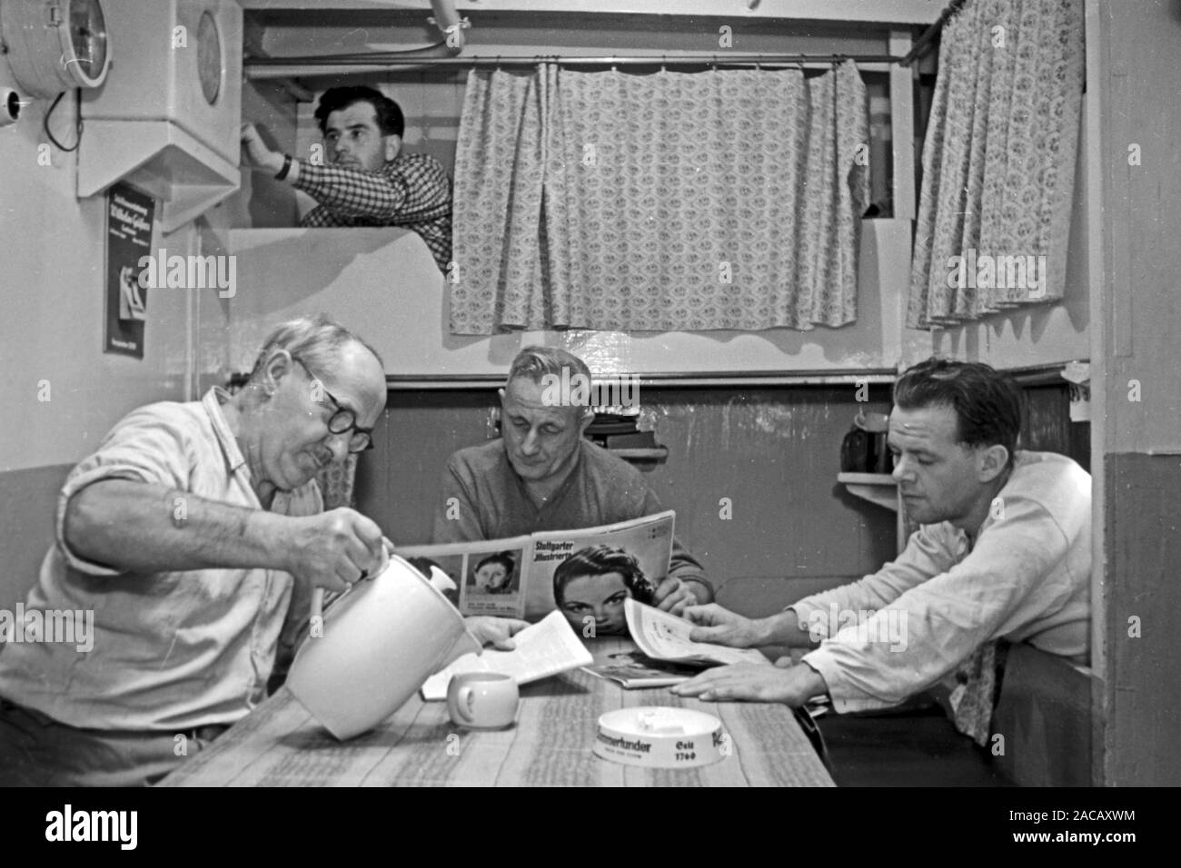 Männer in Kajüte trinken Kaffee und lesen Zeitung, Emden, Niedersachsen, Deutschland, 1950. Gli uomini in cabina bere un caffè e leggere il giornale, Emden, Bassa Sassonia, Germania, 1950. Foto Stock