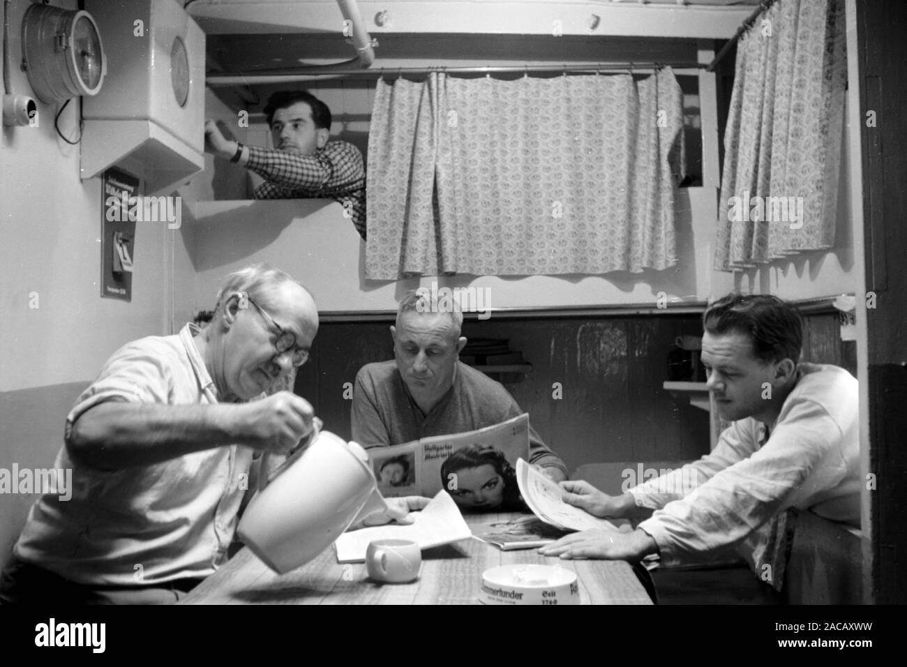 Männer in Kajüte trinken Kaffee und lesen Zeitung, Emden, Niedersachsen, Deutschland, 1950. Gli uomini in cabina bere un caffè e leggere il giornale, Emden, Bassa Sassonia, Germania, 1950. Foto Stock