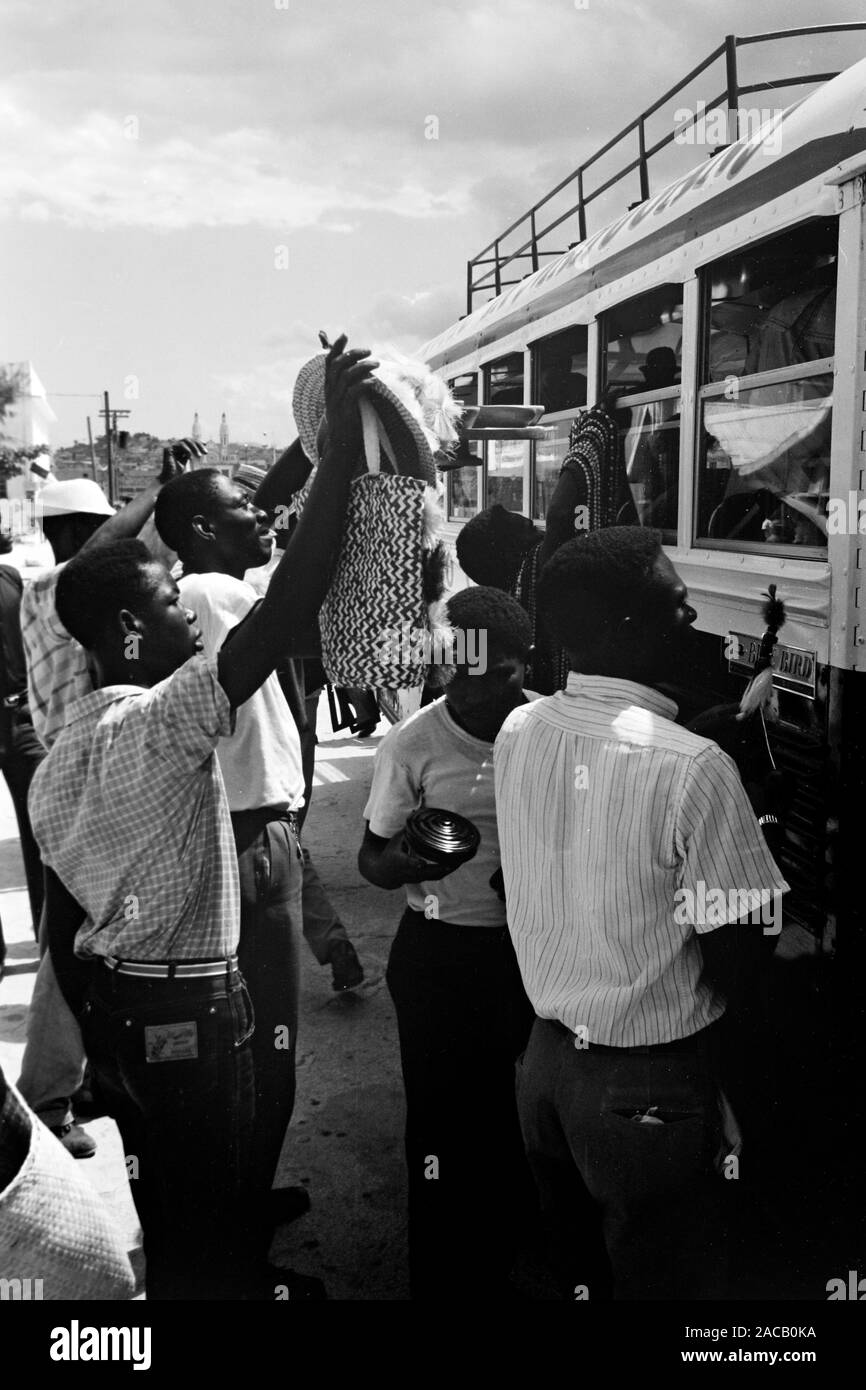 Fliegende Händler bieten ihre Waren durchreisenden Bus-Fahrgästen un, 1967. Gli operatori mobili che offrono la loro merce per i passeggeri di un autobus in transito, 1967. Foto Stock