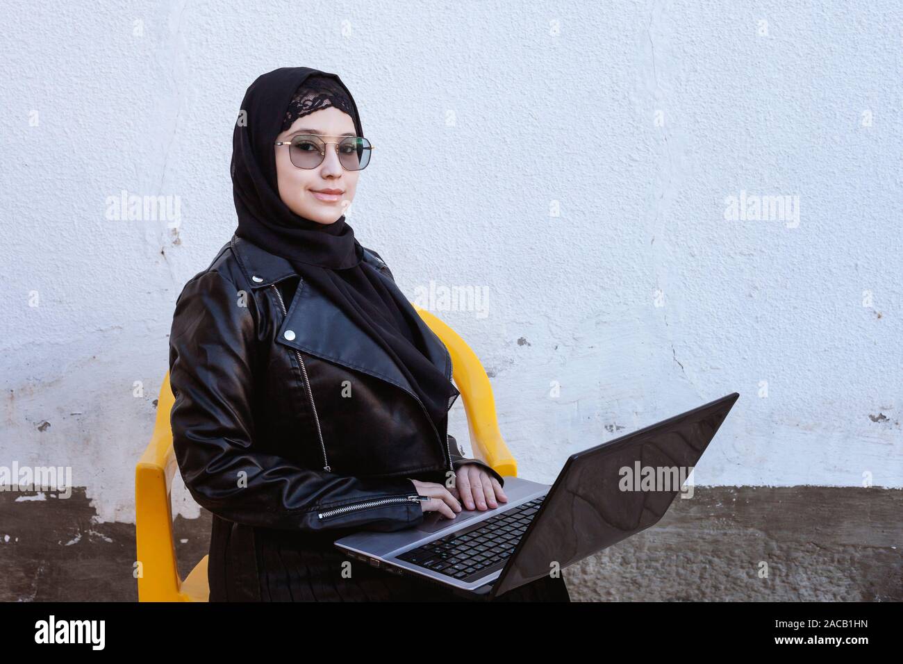 Bella medio-orientali a lavorare con il computer portatile. Carino Arabian donna musulmana in hijab in posa con il computer portatile all'esterno. Blogger, vlogger, freelancer alla ragazza Foto Stock