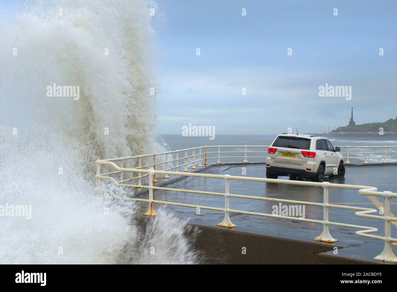 Aberystwyth Ceredigion nel Galles/UK Novembre 28 2019: Jeep veicolo parcheggiato sul mare con onde alte la frenata sul mare muro di difesa. Foto Stock