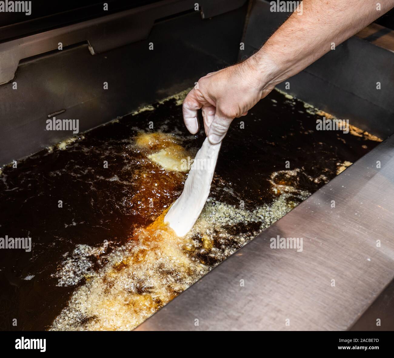 I pesci batterizzati sono messi in una friggitrice a grasso profondo in un negozio di pesci e chip nel Regno Unito Foto Stock