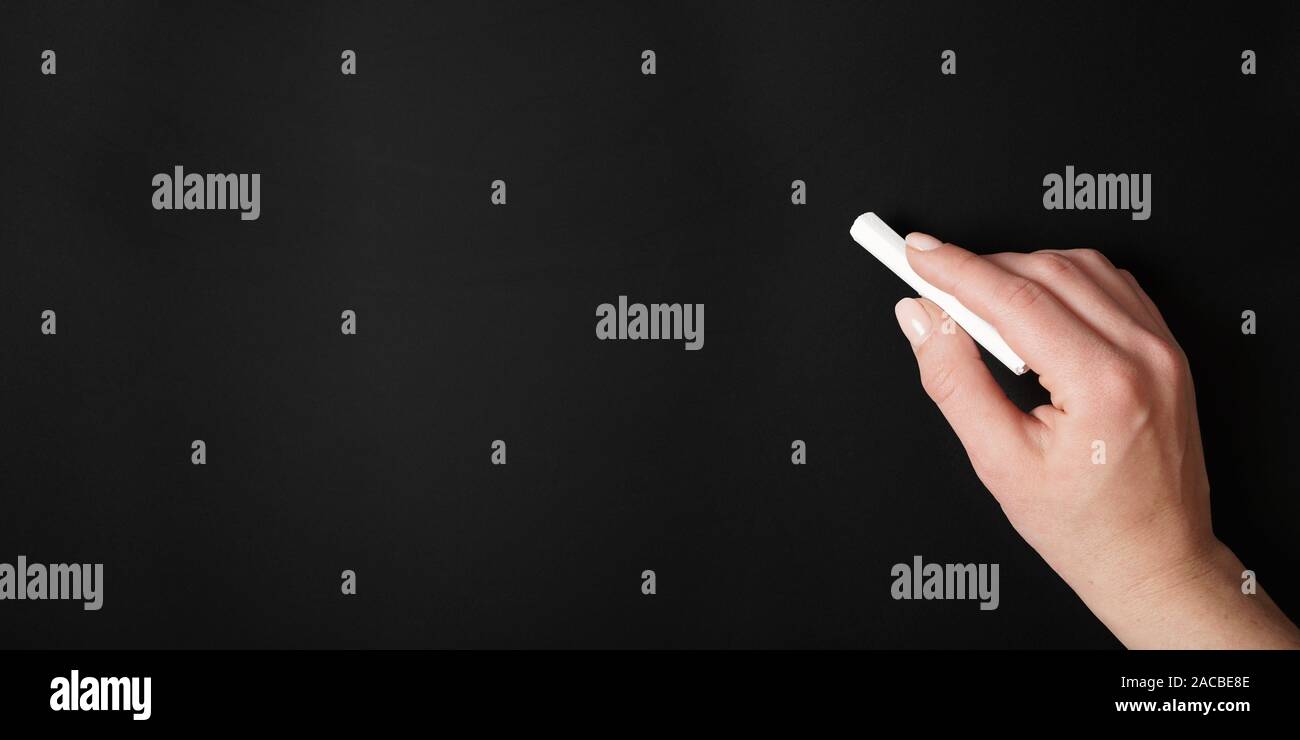 Mano femminile contro il gesso bianco sullo sfondo della scheda Foto Stock