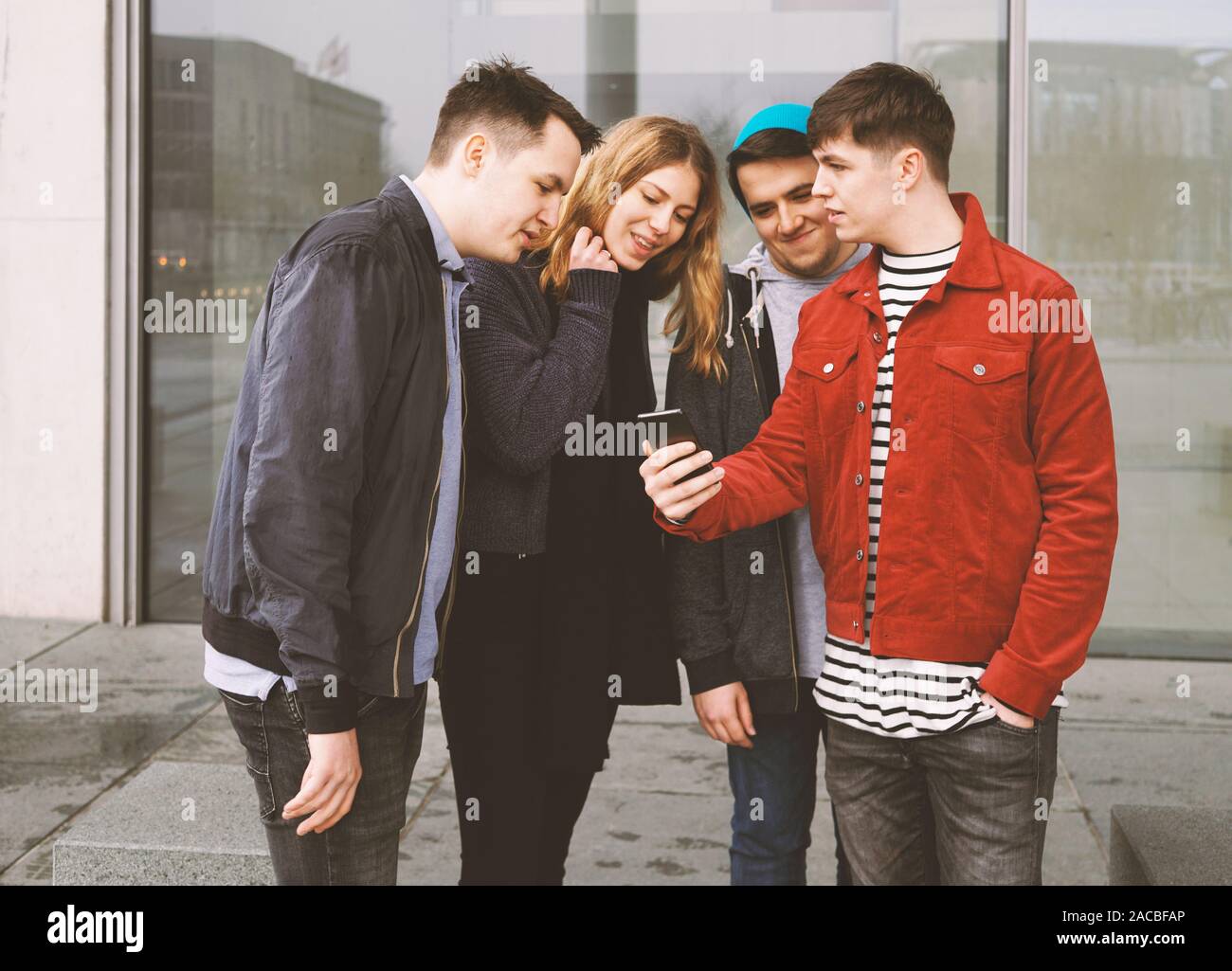Giovane uomo che mostra qualcosa sul suo cellulare per un gruppo di amici - urban lifestyle teenage Foto Stock