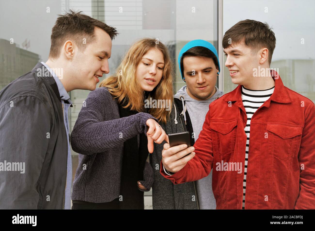 Gruppo di amici adolescenti avente una discussione su alcuni telefoni contenuto - giovane donna rivolta verso lo schermo dello smartphone Foto Stock