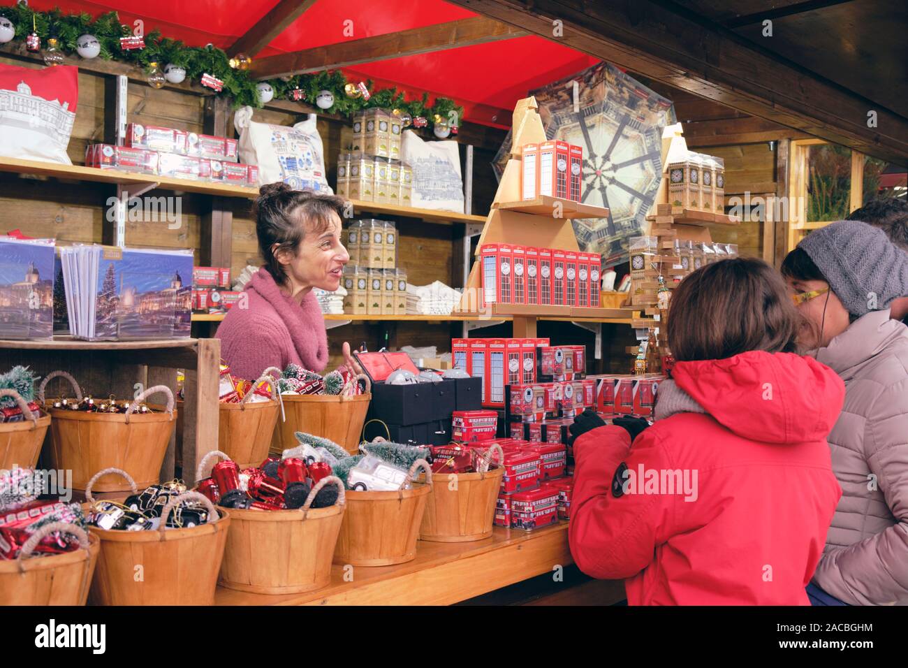 Mercatino di Natale di stallo Londra Vendita di souvenir di immagine in Trafalgar Square con il venditore e due per turisti in cerca a Ware. Londra, Regno Unito, Foto Stock