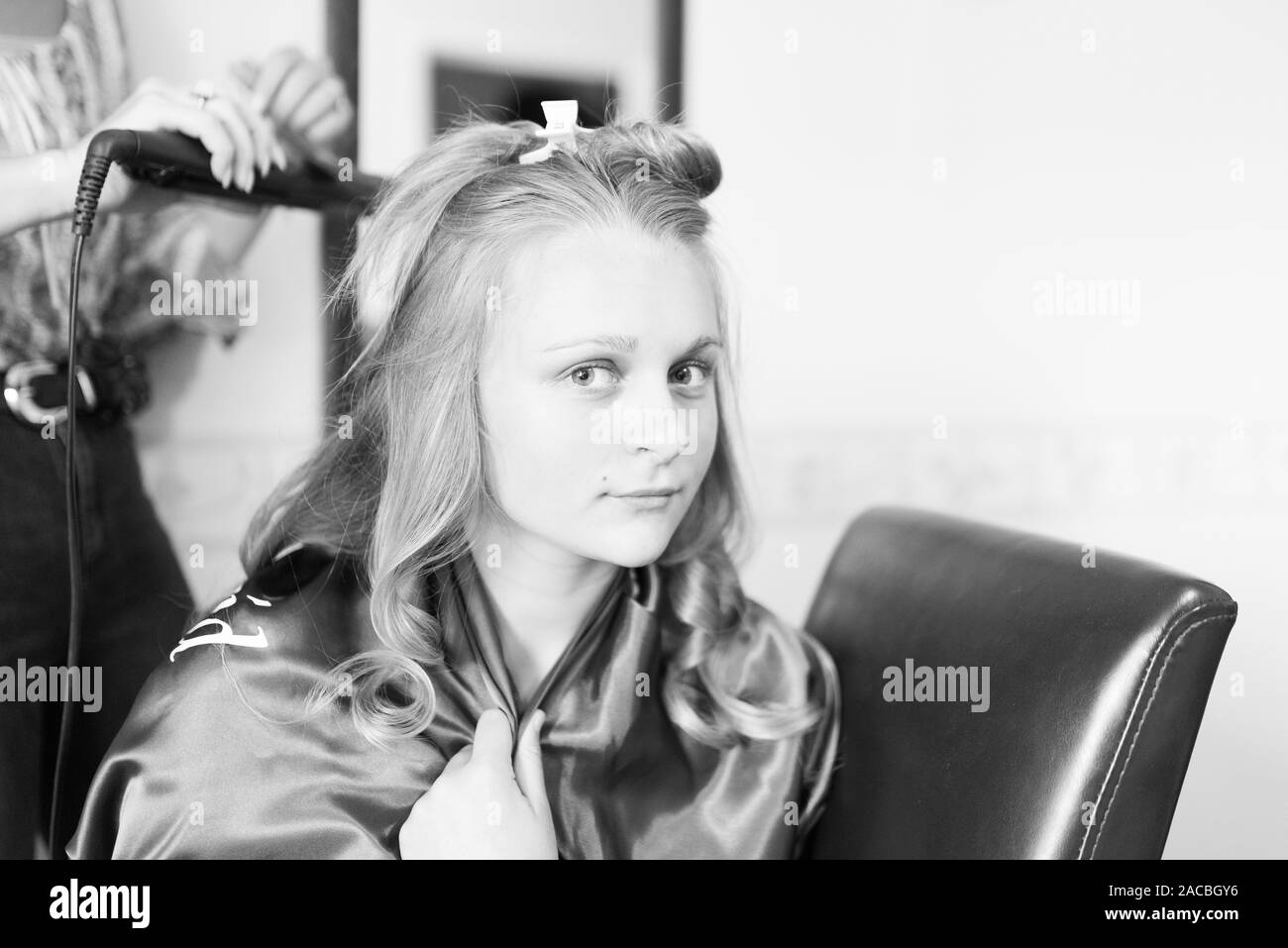 Una graziosa bridesmaid che si prepara per il giorno di nozze avanti, avendo i suoi capelli e trucco fatto, preparazione nuziale, preparazione nuziale Foto Stock