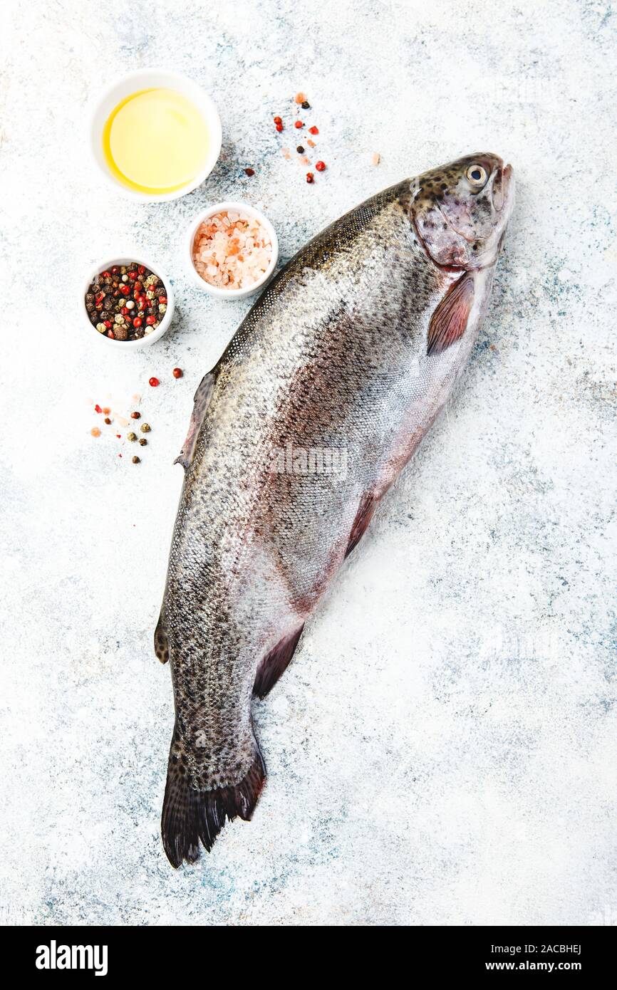 Fresco iridato materie trote con grani di pepe, olio d'oliva, sale himalayano su sfondo chiaro. Cibo sano. Concetto di cucina a vista. Vista dall'alto. Foto Stock