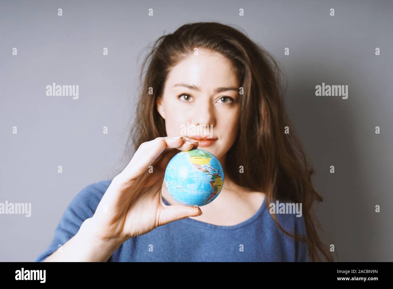 Giovane donna azienda Globo mondo nella sua mano - viaggio o di protezione ambientale o ragazza concetto di potenza Foto Stock