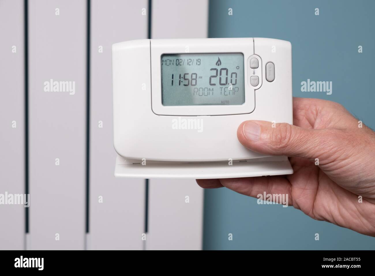 Mano che tiene il riscaldamento centrale con controller moderno pannello del radiatore in background Foto Stock