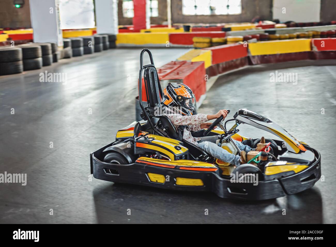 Intrattenimento per bambini in ambienti chiusi. Ragazza la guida go kart su pista. Uno stile di vita attivo. Foto Stock