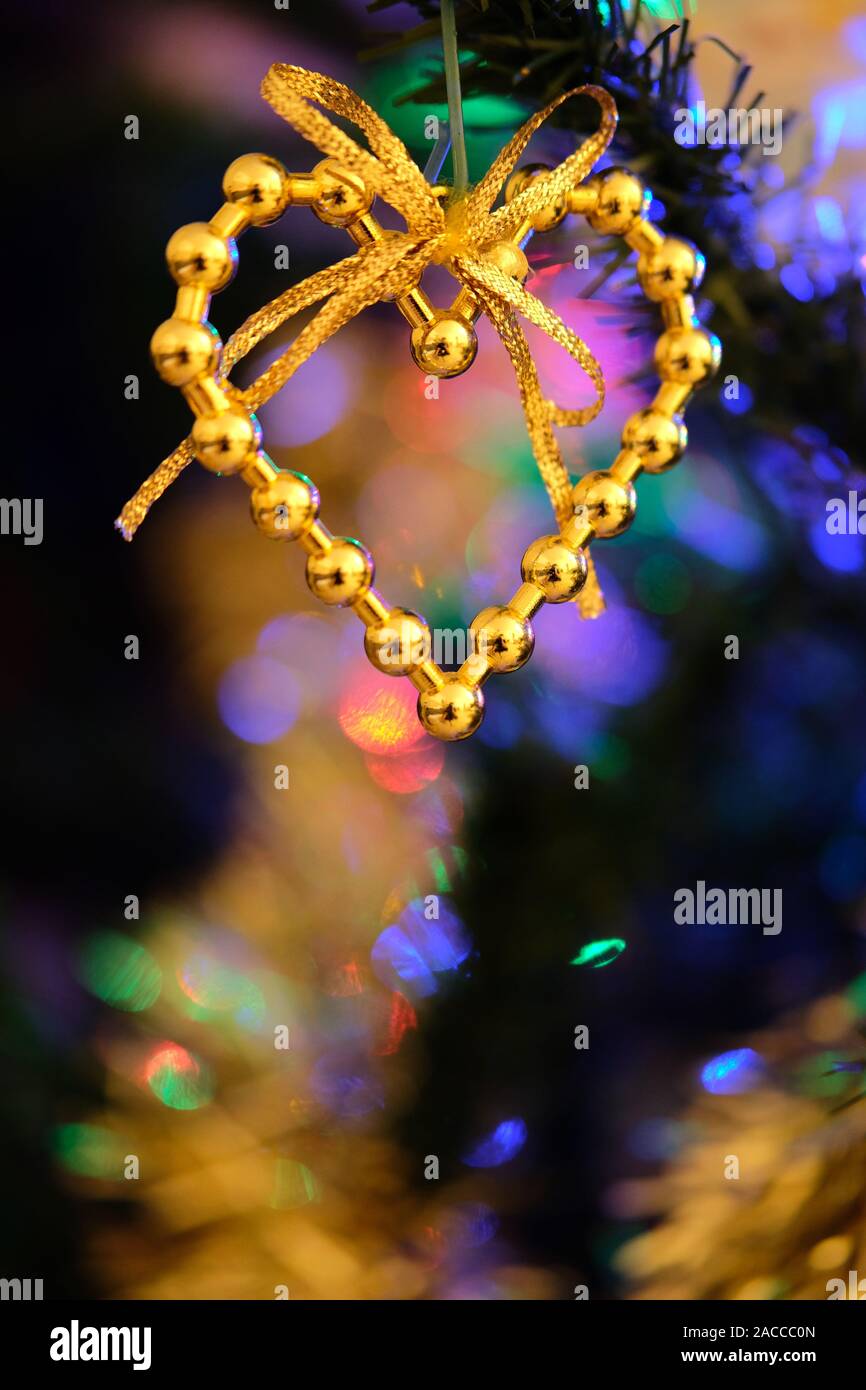 A forma di cuore ad ornamento di Natale appeso su un graziosamente decorate albero di Natale Foto Stock