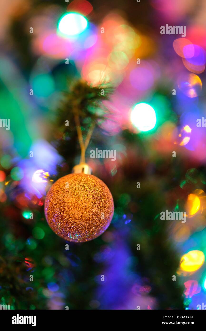 Orange palla di Natale decorazione su un albero di Natale con intensa sfocata o sfondo bokeh di fondo Foto Stock