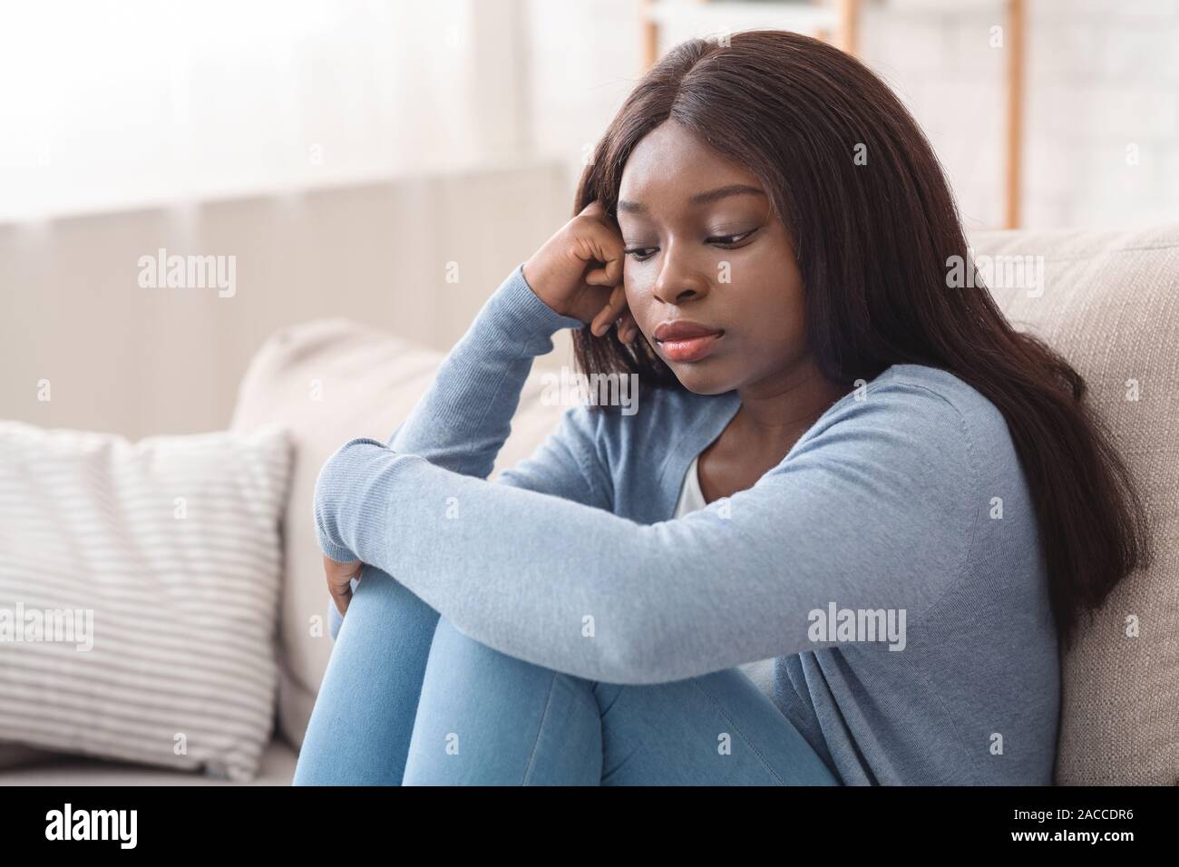 Sconvolto nero ragazza seduta sul divano con la faccia pensosa espressione Foto Stock