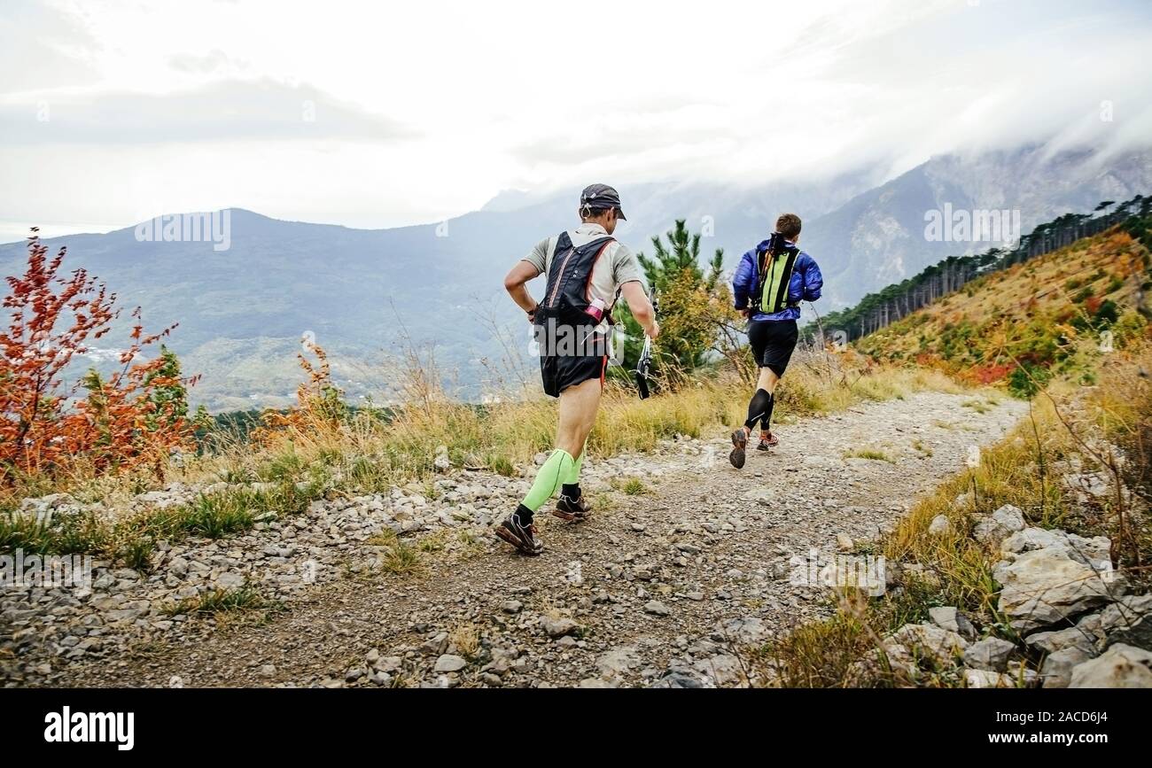 Indietro di due uomini runner con zaini eseguire il sentiero di montagna caduta Foto Stock
