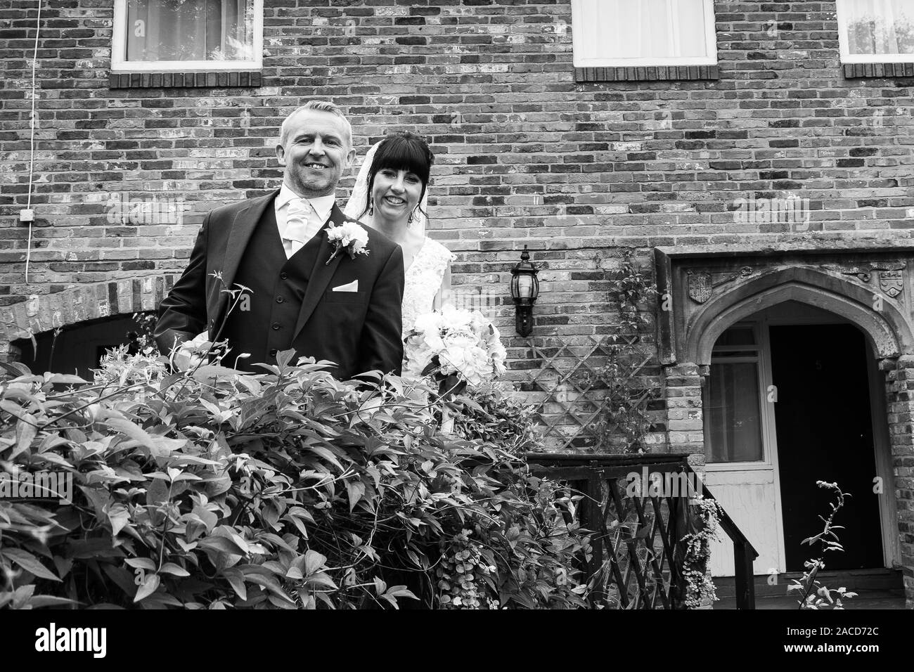 La sposa e gli sposi posano per le loro foto dopo la cerimonia nei giardini dell'hotel Manor, B&B a Cheadle, Stoke on Trent, Staffordshire, giorno delle nozze Foto Stock