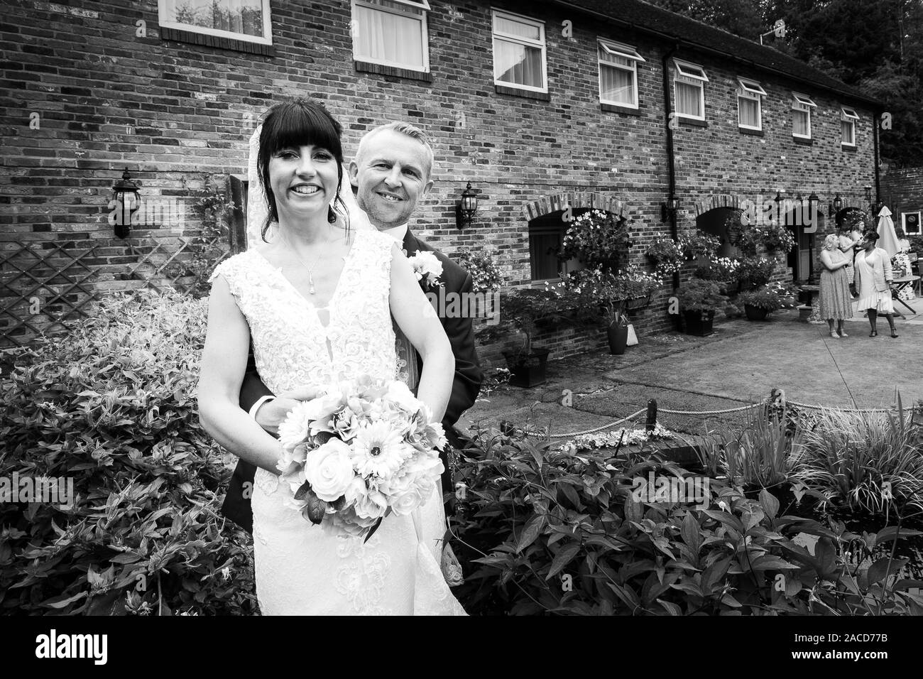 La sposa e gli sposi posano per le loro foto dopo la cerimonia nei giardini dell'hotel Manor, B&B a Cheadle, Stoke on Trent, Staffordshire, giorno delle nozze Foto Stock