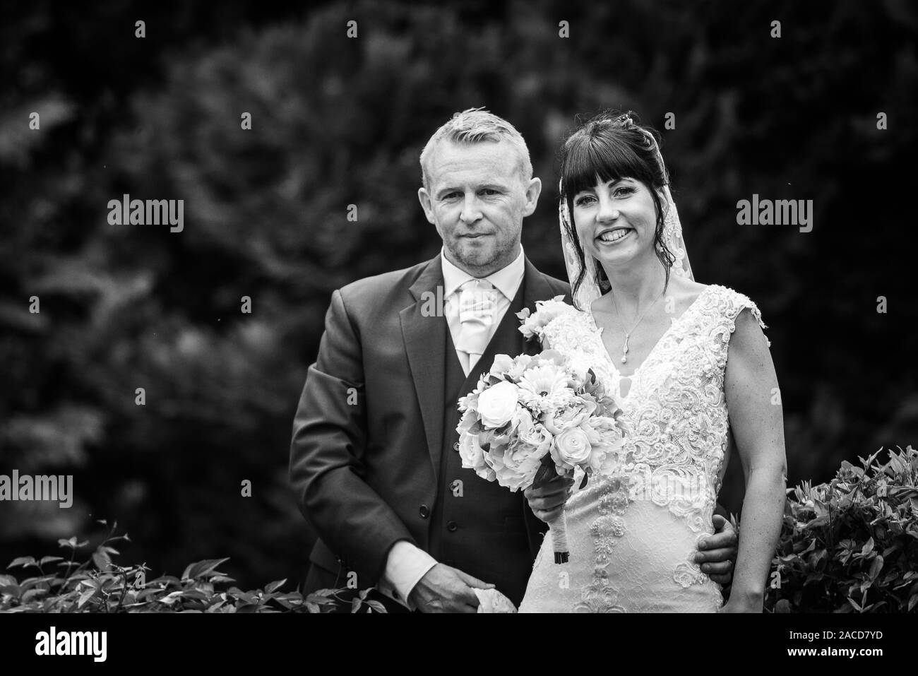 La sposa e gli sposi posano per le loro foto dopo la cerimonia nei giardini dell'hotel Manor, B&B a Cheadle, Stoke on Trent, Staffordshire, giorno delle nozze Foto Stock