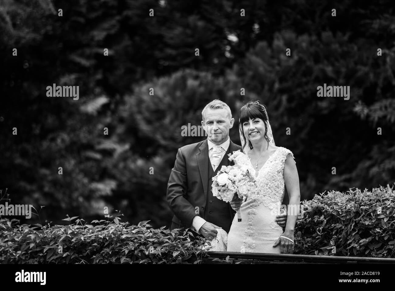 La sposa e gli sposi posano per le loro foto dopo la cerimonia nei giardini dell'hotel Manor, B&B a Cheadle, Stoke on Trent, Staffordshire, giorno delle nozze Foto Stock