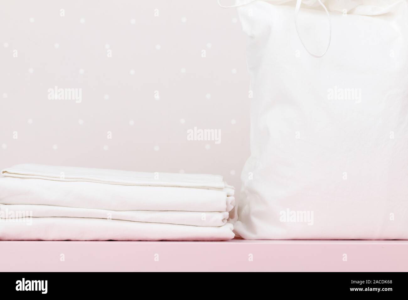 Primo piano di una pila di lenzuola pulite e un sacco di storage su un muro bianco sullo sfondo. Foto Stock