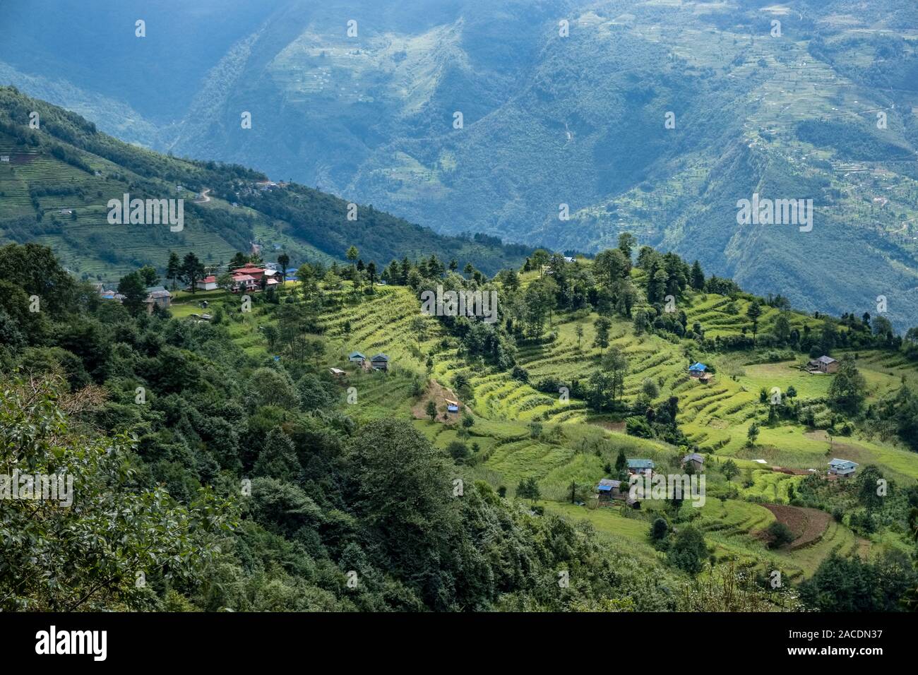 Il villaggio con case e campi di terrazza, pendii montani e le foreste in distanza Foto Stock